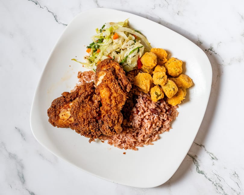Fried chicken, rice and beans, fried okra, and coleslaw on a white plate.